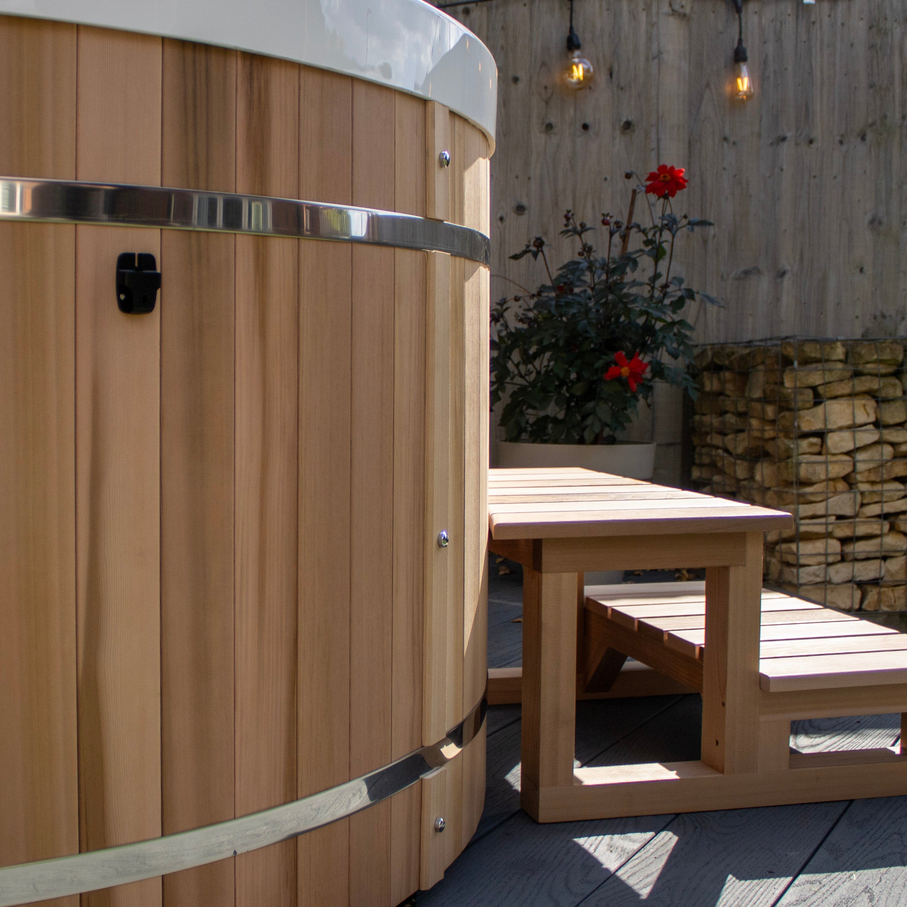 Wooden hot tub with a wooden bench in an outdoor setting