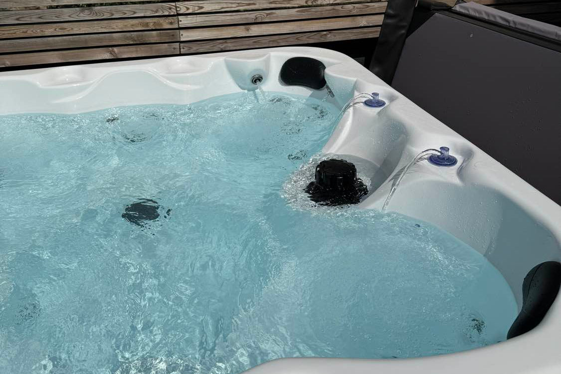 Hot tub with water in a backyard setting against a wooden fence