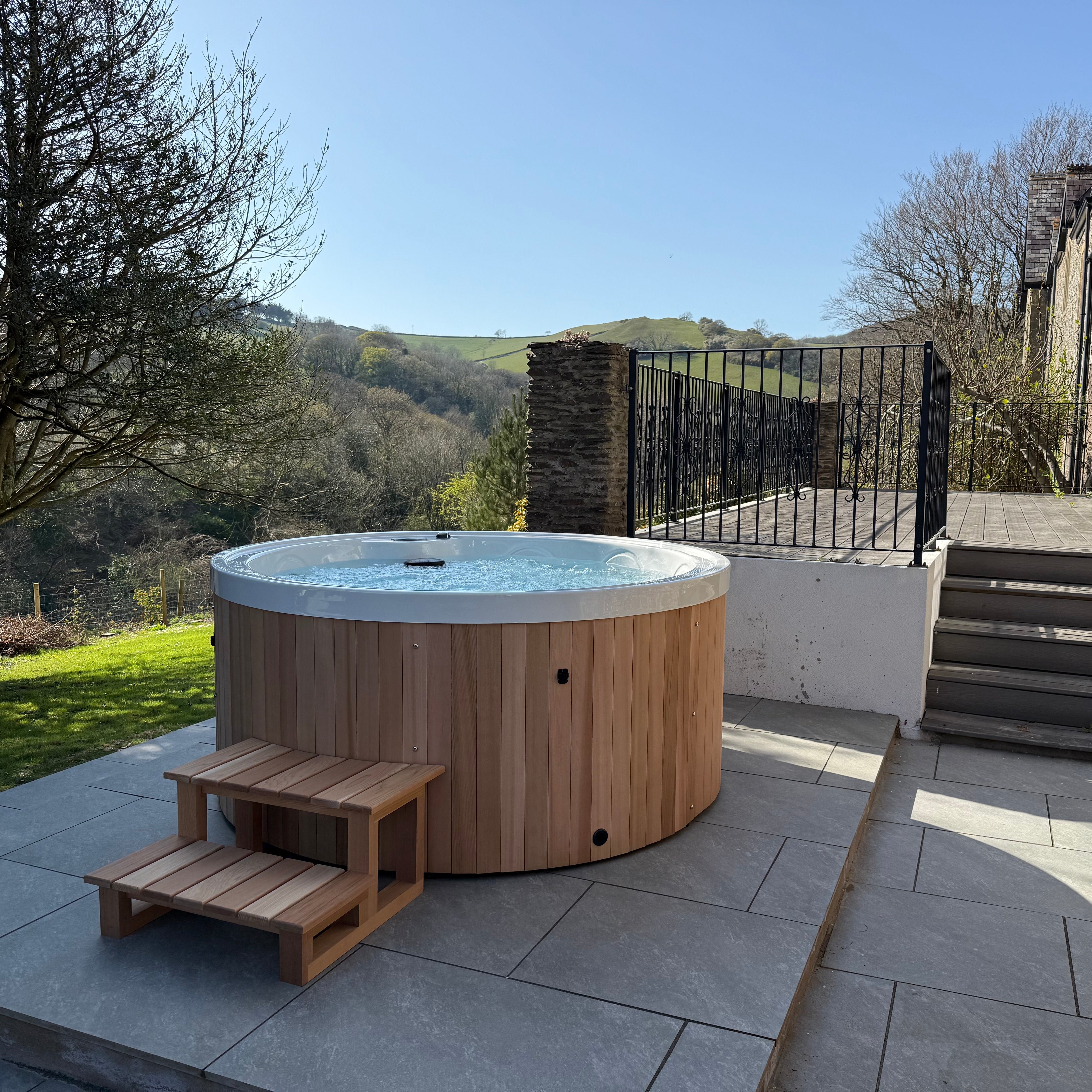 Hot tub on a patio area with a scenic background